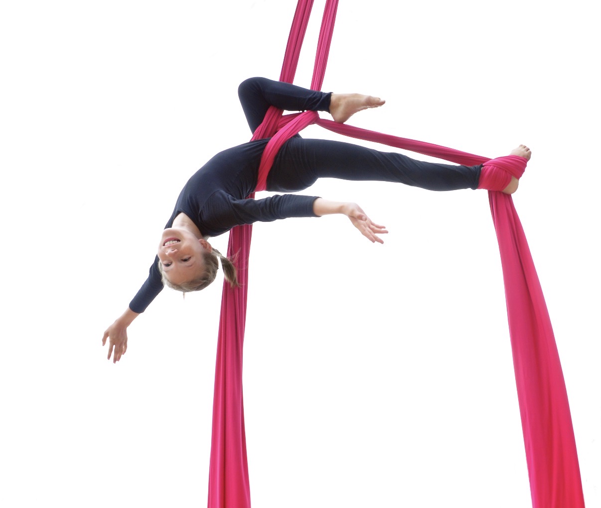 Niña realizando una figura en telas aéreas rosas.